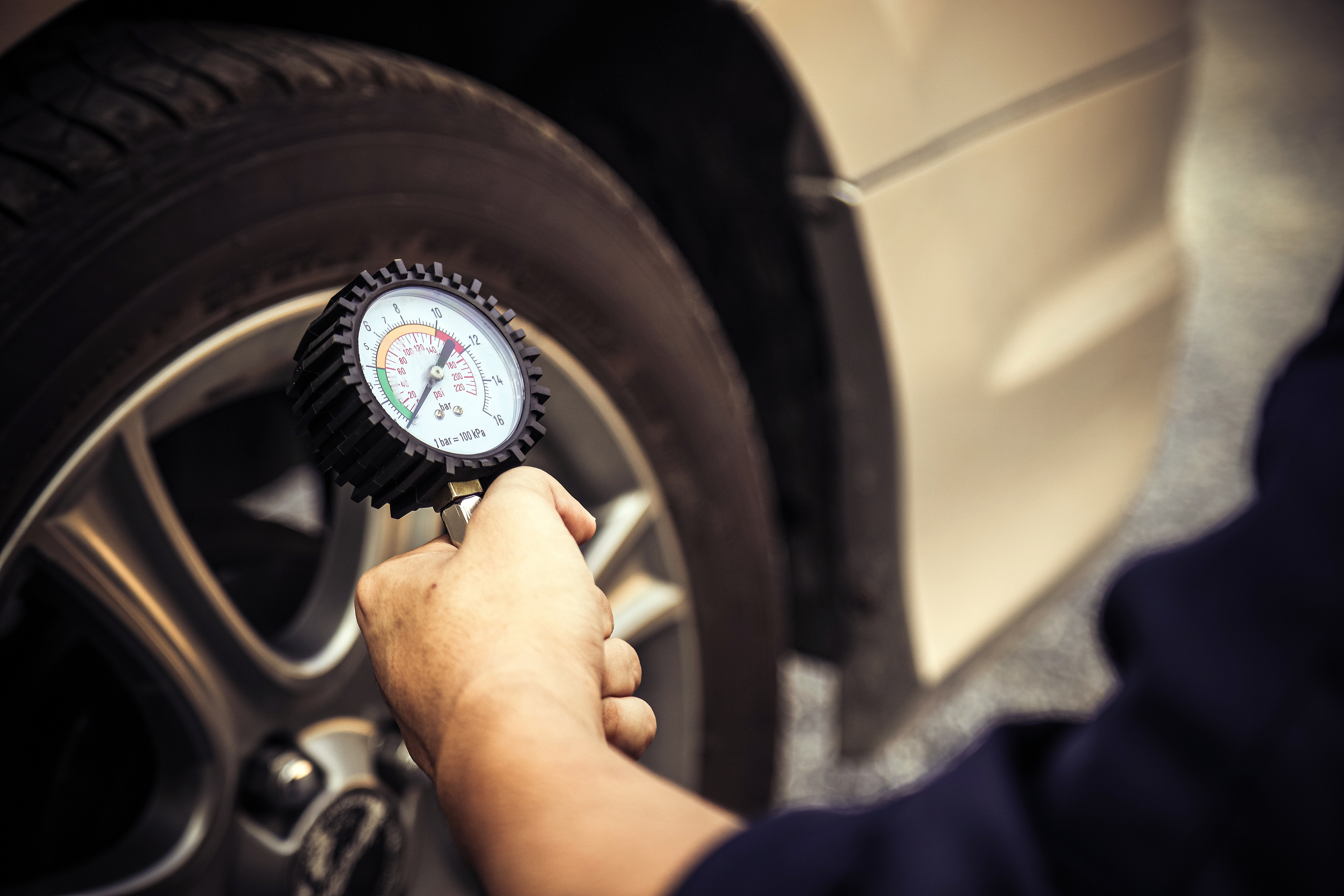 A man checking the tire pressure of a vehicle